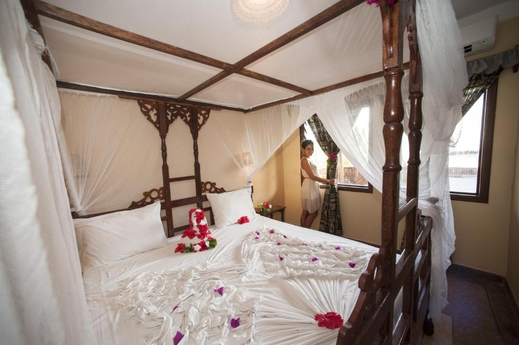 a woman standing in a bedroom with a bed at Palumboreef Beach Resort in Uroa