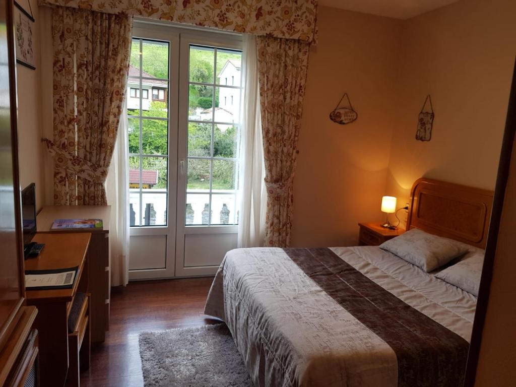 Un dormitorio con una cama y una ventana grande. en Alojamiento Calzada Romana, en Belmonte de Miranda