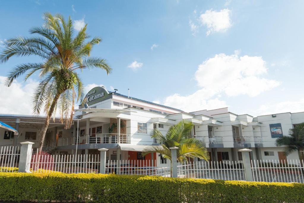 a white building with palm trees in front of it at Hotel Catama Inn in Fusagasuga