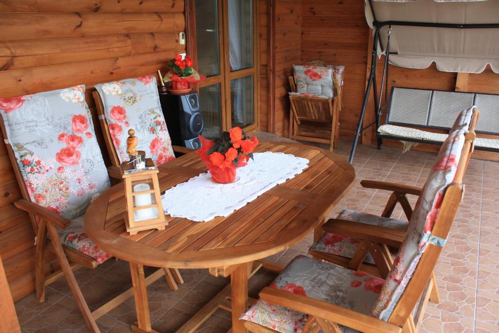 a wooden table and chairs on a porch with a table and flowers at Kama Pokoje Gościnne in Białowieża
