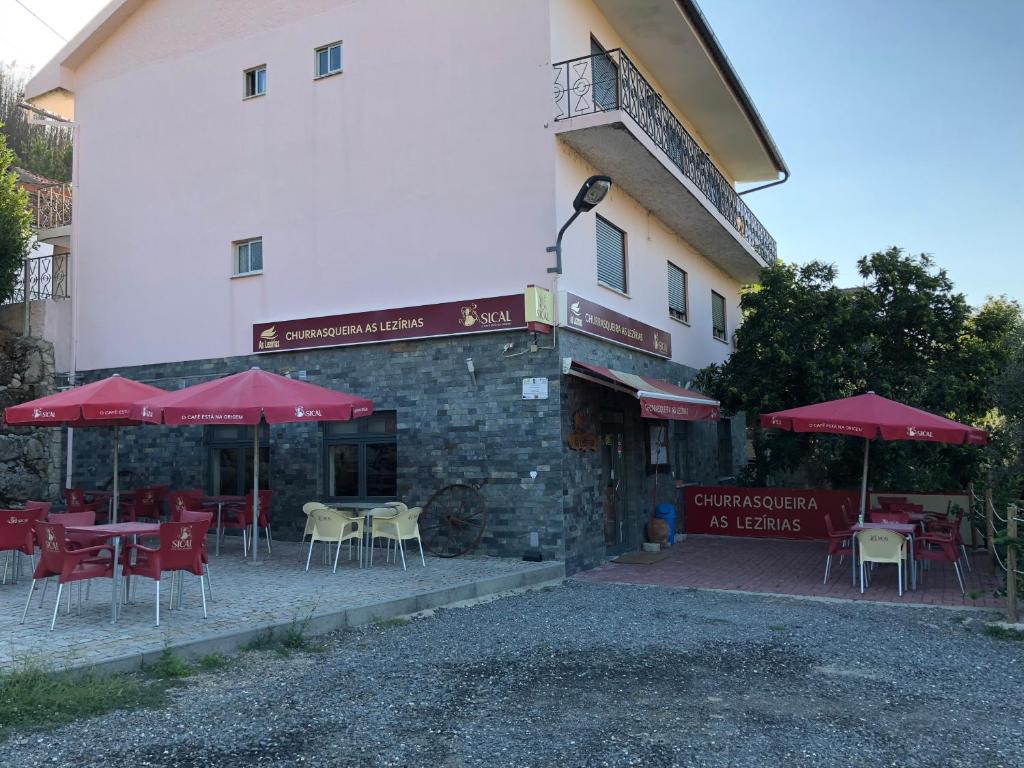 a restaurant with tables and umbrellas in front of a building at Casa das Lezírias in Unhais da Serra