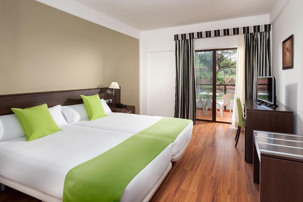 プエルト・デ・ラ・クルスにあるTRH Taoro Garden - Only Adultsの大型ベッドとテレビが備わるホテルルームです。