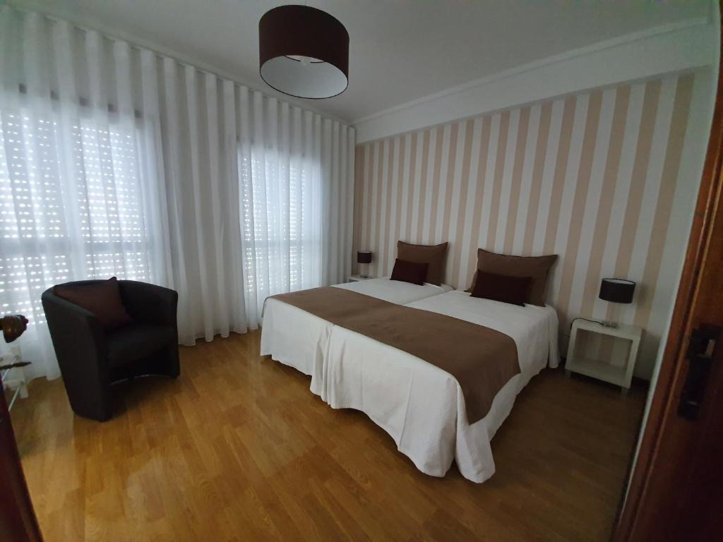 1 dormitorio con 1 cama grande y 1 silla en Casa Dos Arcos, en Aveiro