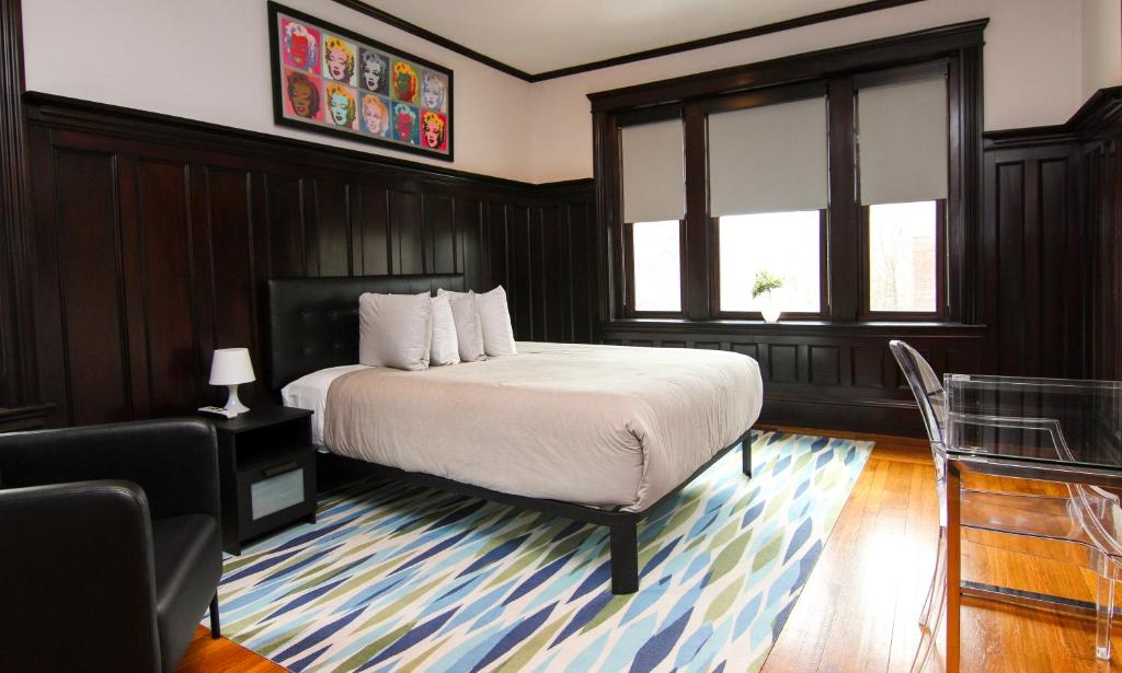 a bedroom with a bed and a chair and windows at A Stylish Stay with a King Bed and Heated Floors #27 in Brookline