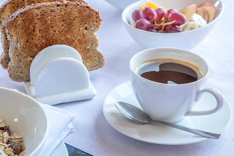 uma chávena de café num prato com uma tigela de pão em Maxwelston Farmhouse em Girvan