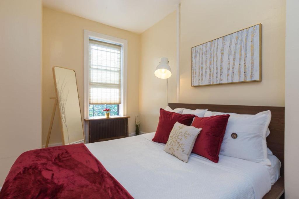 een slaapkamer met een groot bed met rode kussens bij Lavish 3 Bedroom Apt in Williamsburg!! in Brooklyn
