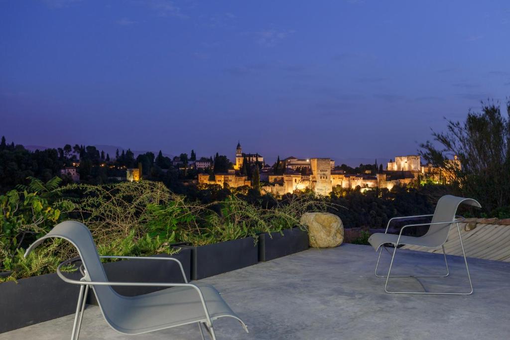 2 sedie sedute su un patio di notte di Casa Cueva Lujo Sacromonte con vistas Alhambra a Granada