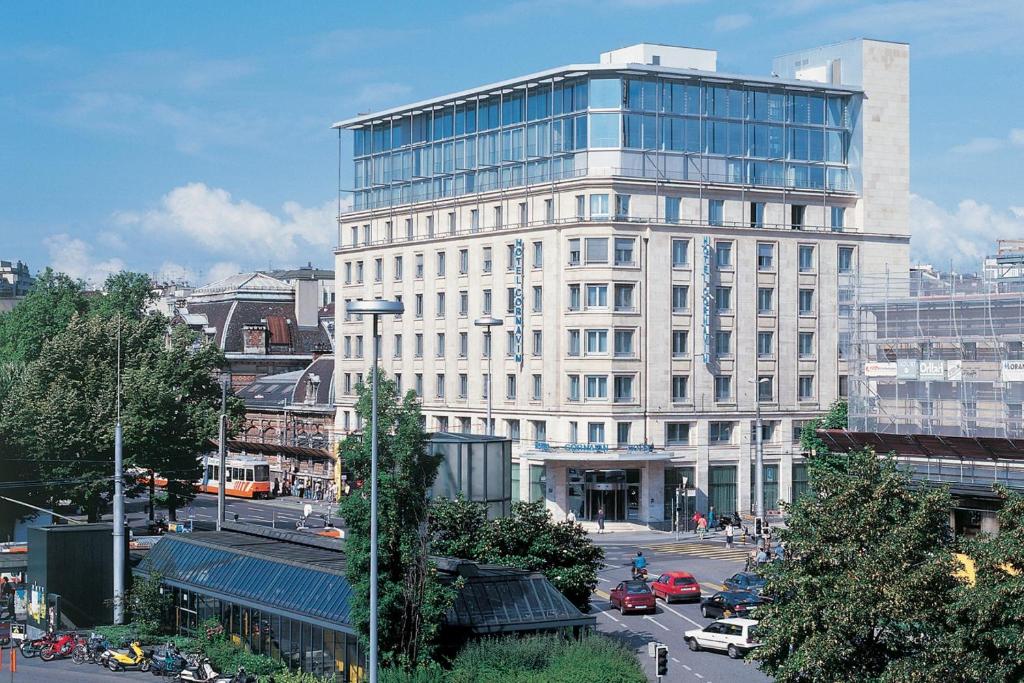 un grand bâtiment blanc avec une rue en face dans l'établissement Hotel Cornavin, à Genève