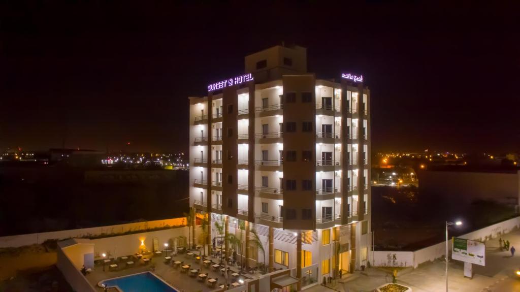 ein Hotel in der Nacht mit Pool davor in der Unterkunft SUNSET HOTEL in Nouakchott
