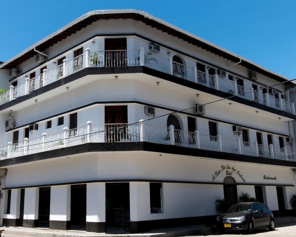 Un bâtiment blanc avec une voiture garée devant. dans l'établissement Hotel Casa de las Dos Palmas -Hotel Boutique, à Puerto Berrío