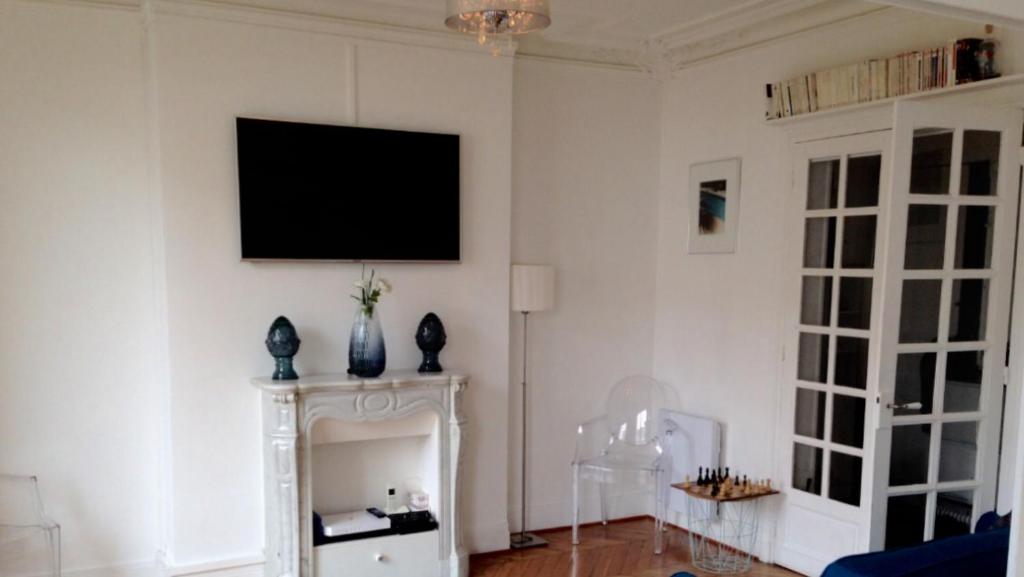 un salon avec une télévision sur un mur blanc dans l'établissement Appartement typiquement parisien, à Paris