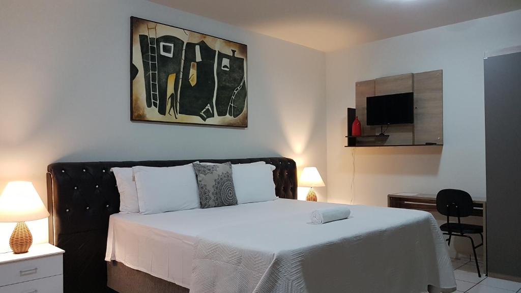 een slaapkamer met een bed met witte lakens en een televisie bij B & A Suites Inn Hotel - Quarto Luxo Platinum in Anápolis