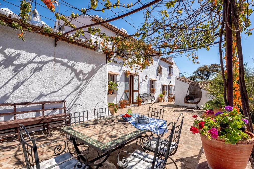 d'une terrasse avec une table, un banc et des fleurs. dans l'établissement Lagar los Pilones, à Casabermeja