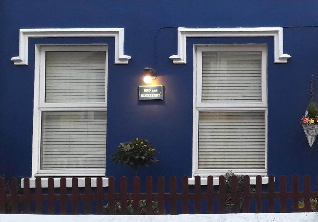 a blue building with two windows and a fence at Blueberry Two Bedroom Suite in Douglas