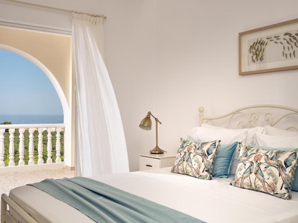 a bedroom with a bed with a view of the ocean at Villaggio Studios & Apartments in Vasilikos