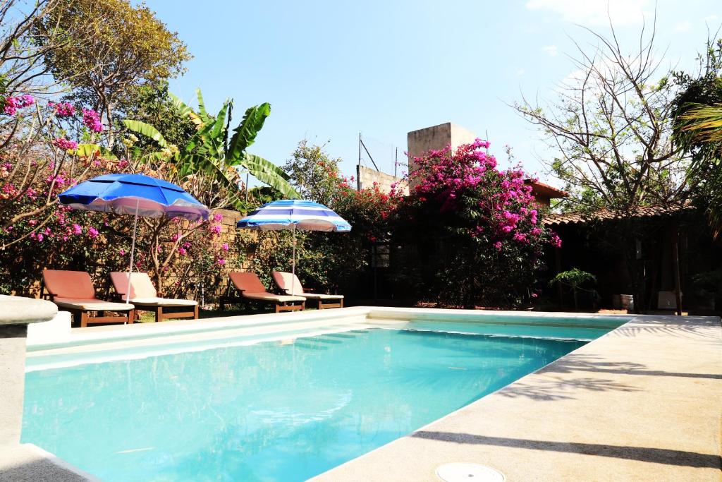 a swimming pool with two umbrellas and chairs at Hotel Casa Pomarrosa in Malinalco