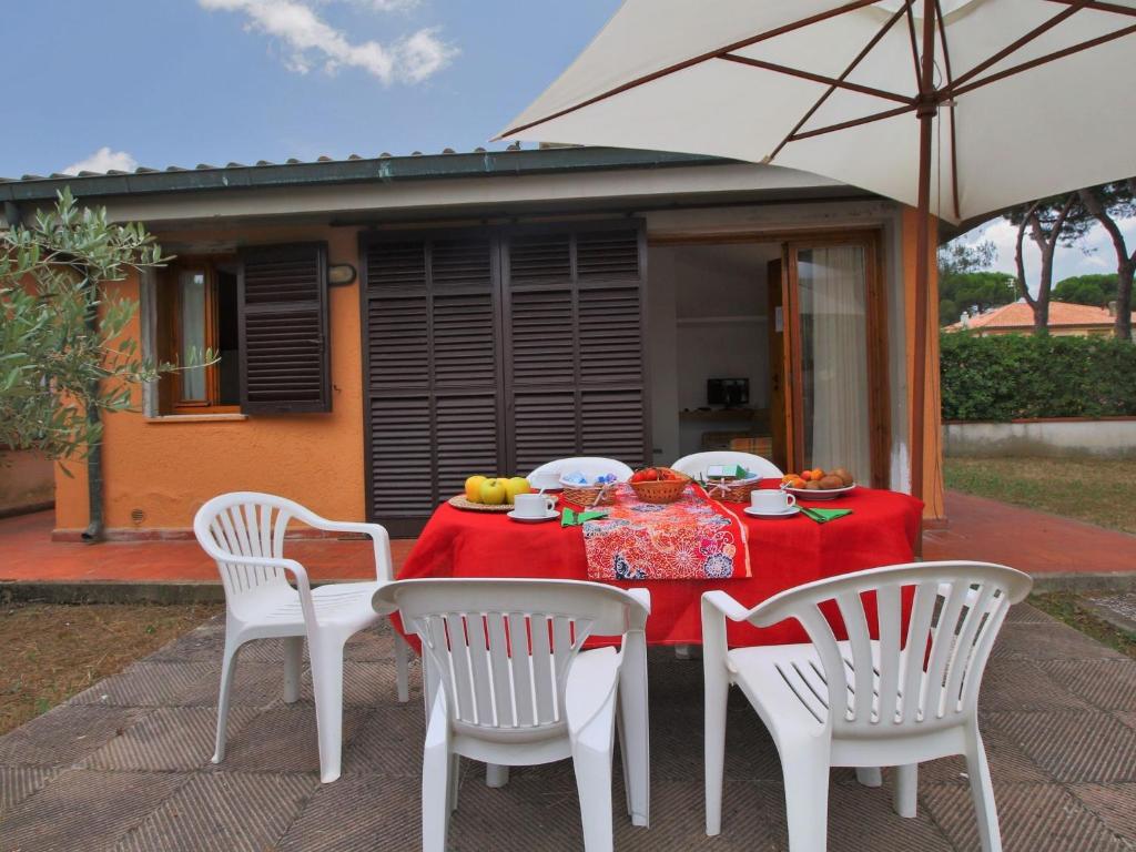 Santa LiberataにあるFlat in villa with air condition close to the beachの赤いテーブルクロスと椅子、傘付きのテーブル
