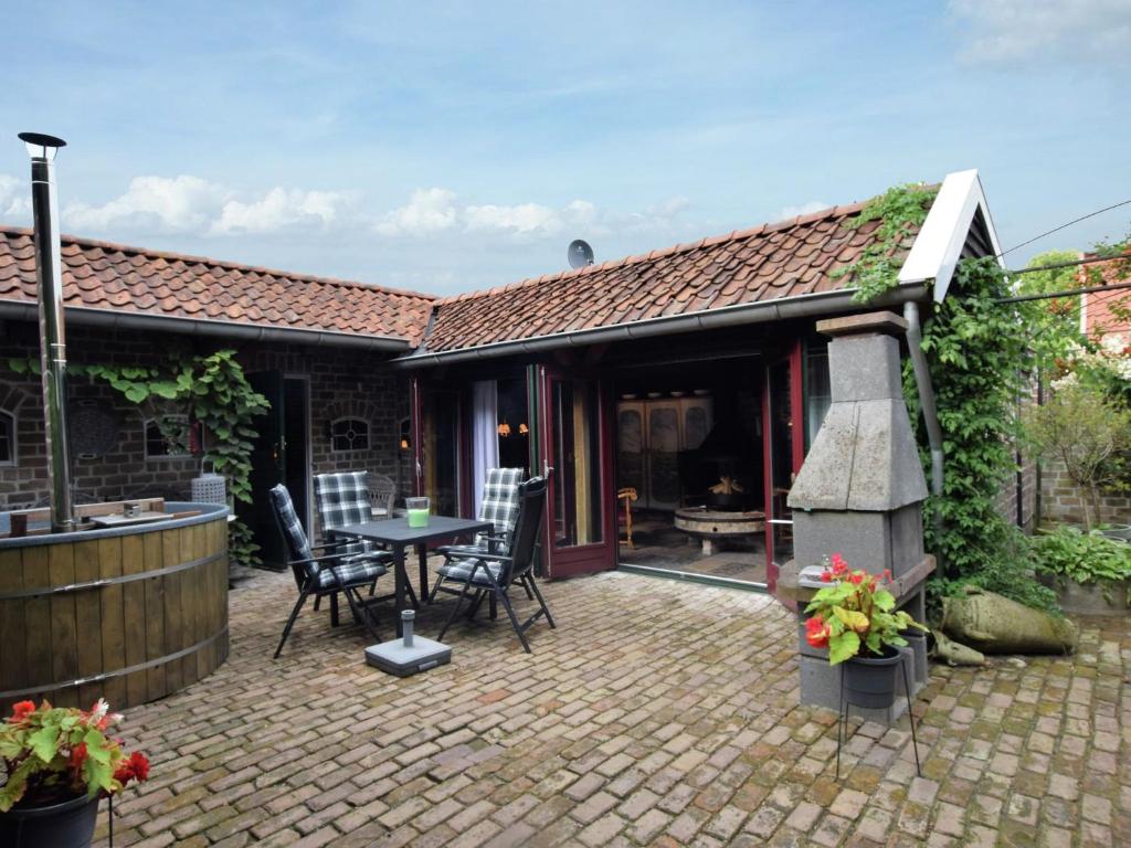 una casa y un patio con mesa y sillas en Cozy holiday home with a hot tub, en Musselkanaal