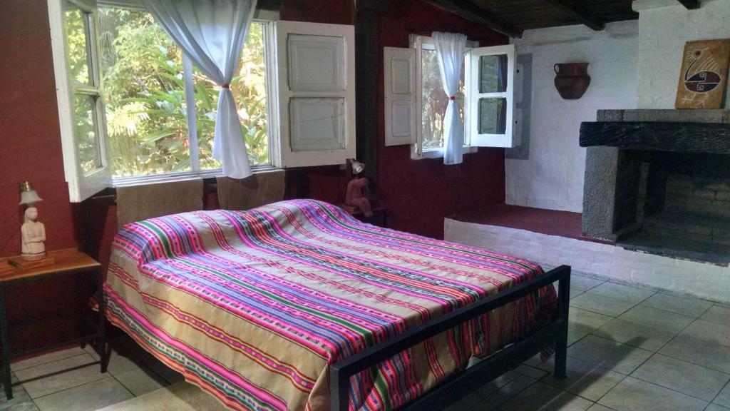 Un dormitorio con una cama con una manta de colores. en El Jardin Colonial en Calilegua