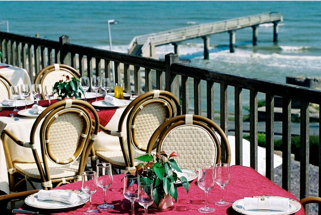 a table with wine glasses and a view of the ocean at Logis Hotel Du Casino Restaurant Le Mathelia in Vierville-sur-Mer