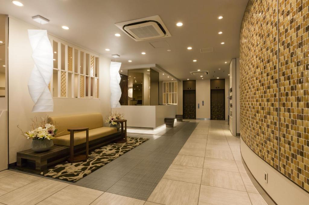a lobby with a couch and a tile wall at Via inn Kyoto Shijomuromachi in Kyoto