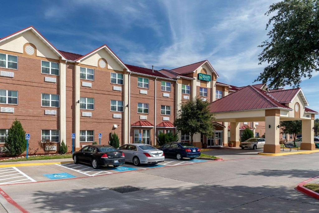um hotel com carros estacionados num parque de estacionamento em Quality Suites Addison-Dallas em Addison