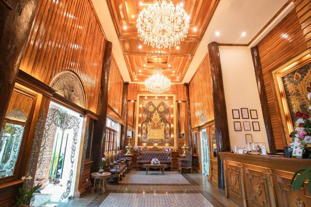 An ornate lobby lounge with wood panelling, chandeliers, framed artwork and a reception counter.