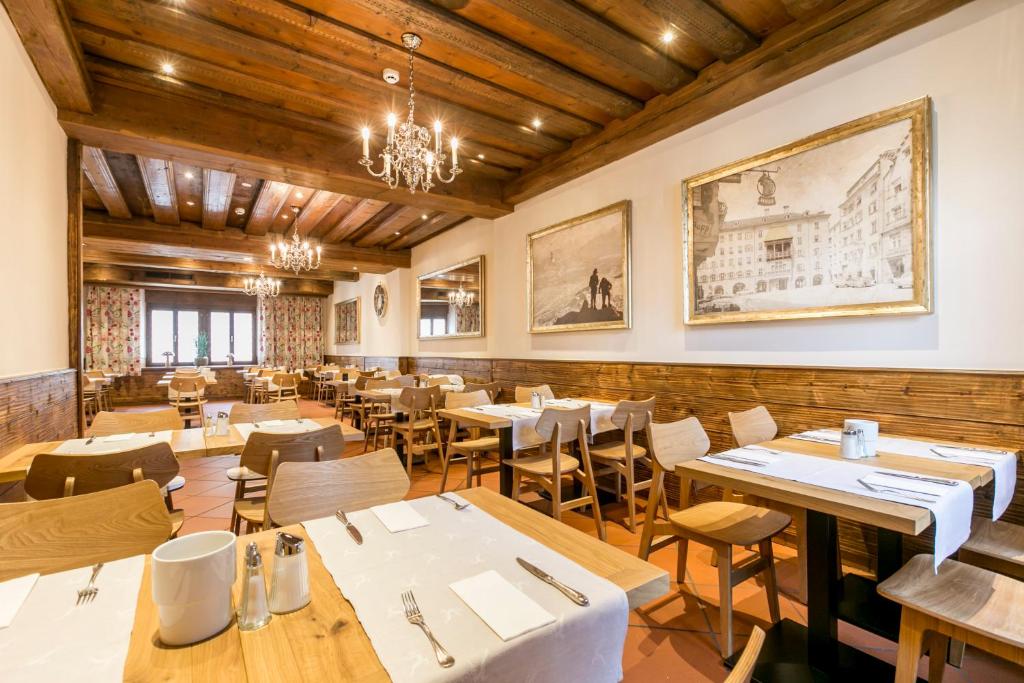 a restaurant with wooden ceilings and tables and chairs at Hotel Sailer in Innsbruck