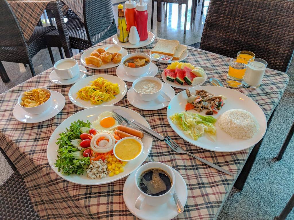 a table with plates of food and drinks on it at Kanokan Hotel in Kanchanaburi City