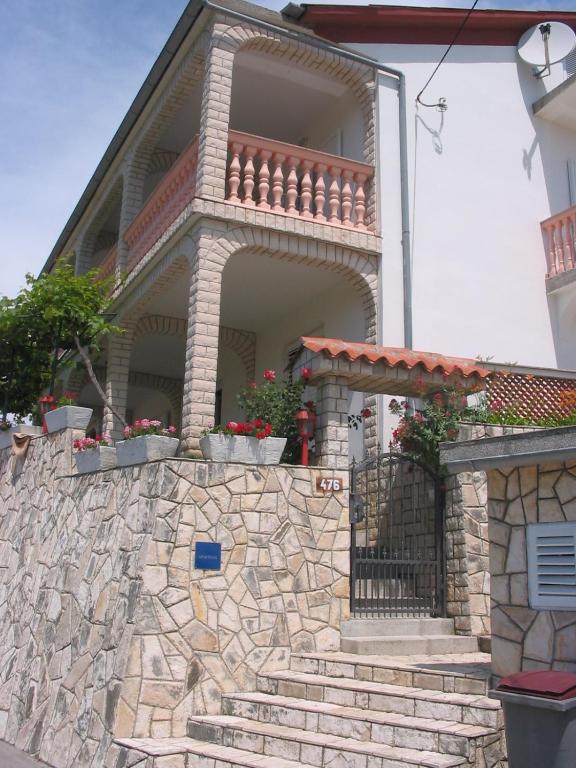 a house with a stone wall and stairs at Apartmani Manuela Lopar in Lopar