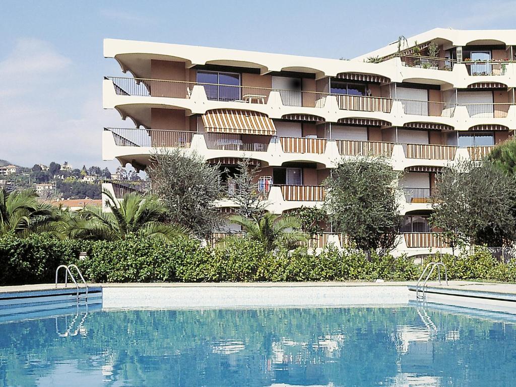 a hotel with a swimming pool in front of a building at Lagrange Vacances Les Trois Rivières in Mandelieu-La Napoule