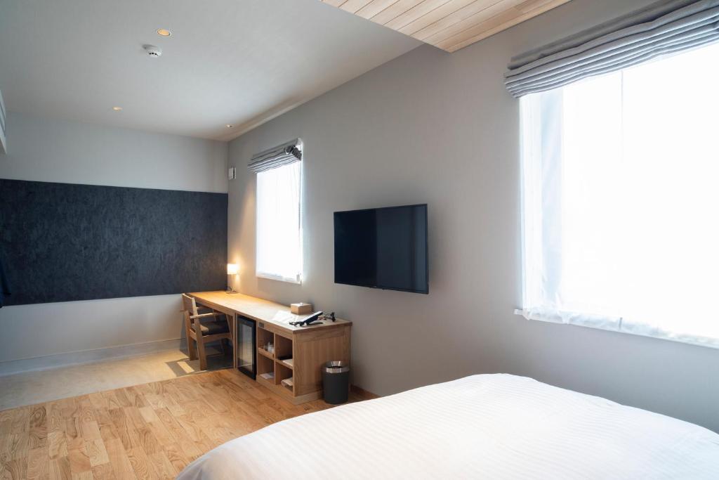 una camera con letto e scrivania con TV di MASCOS HOTEL Masuda Onsen a Masuda