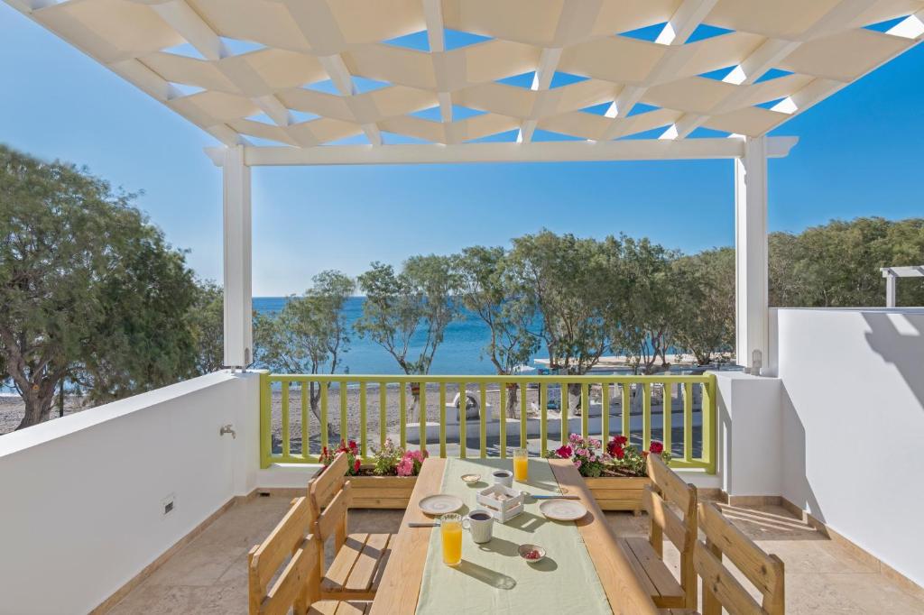 a patio with a table and chairs and a view of the ocean at Parathinalos Beach House in Livadi Astypalaias