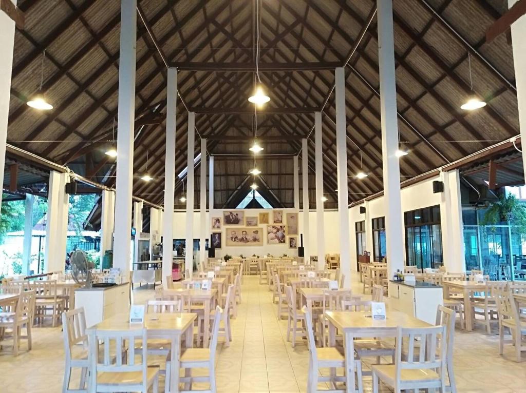 a dining hall with tables and white chairs at LayTrang Pakmeng Marina Spa and Resort in Trang