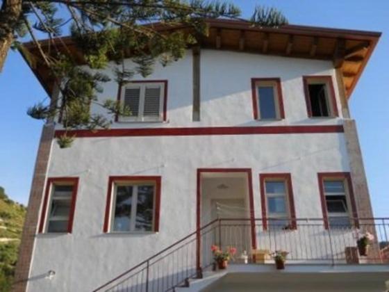 ジョイオーザ・マレーアにあるApartments in Gioiosa Marea/Sizilien 23299の赤い窓とバルコニー付きの大きな白い家
