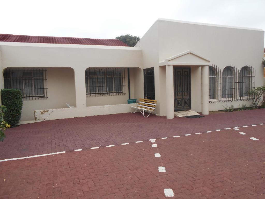 a white building with a brick parking lot in front of it at Pilot Inn Accommodation in Kempton Park