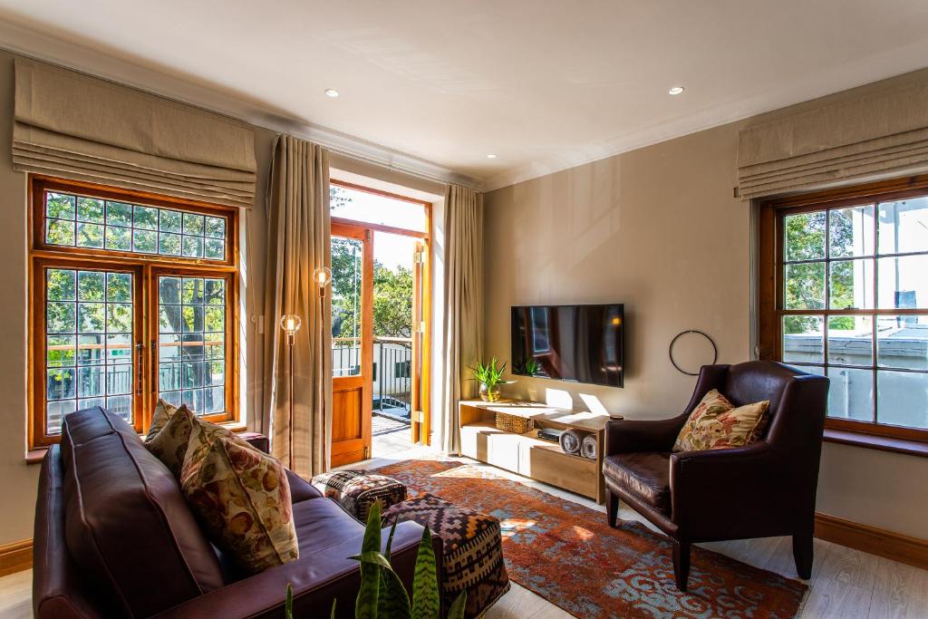 a living room with a couch and chairs and a television at Koetsiershuis in Stellenbosch