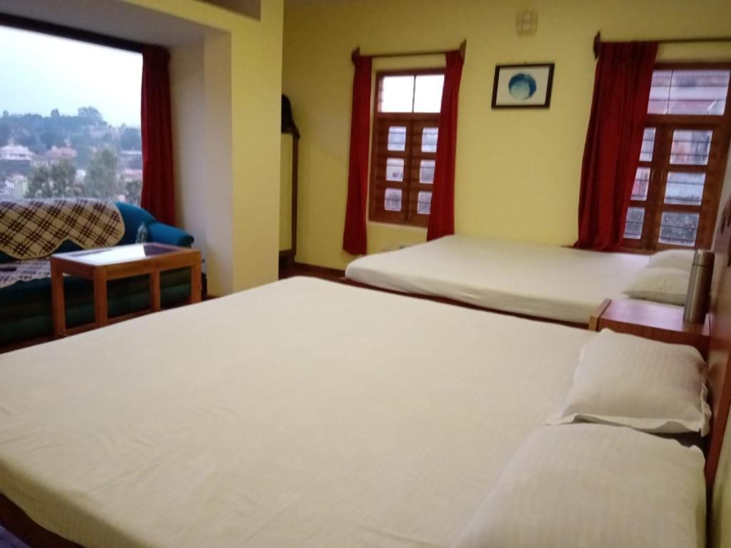 a bedroom with two beds and a table and windows at Satya Anand Cottage Pure veg & non alcoholic Cottage in Coonoor