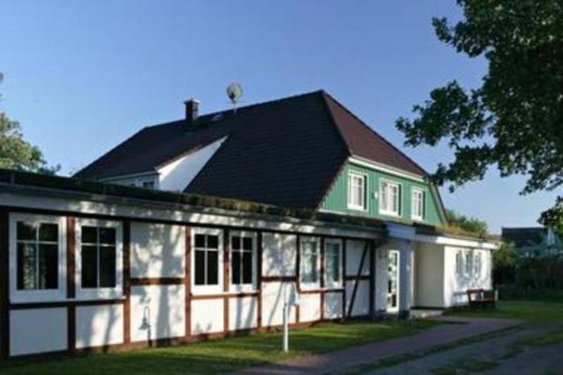 a white and green house with a black roof at Gaestehaus _ Strandhalle in Ahrenshoop