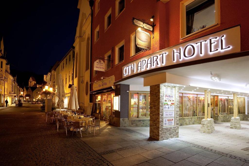 a restaurant with tables and chairs on a street at night at City Apart Hotel Füssen in Füssen
