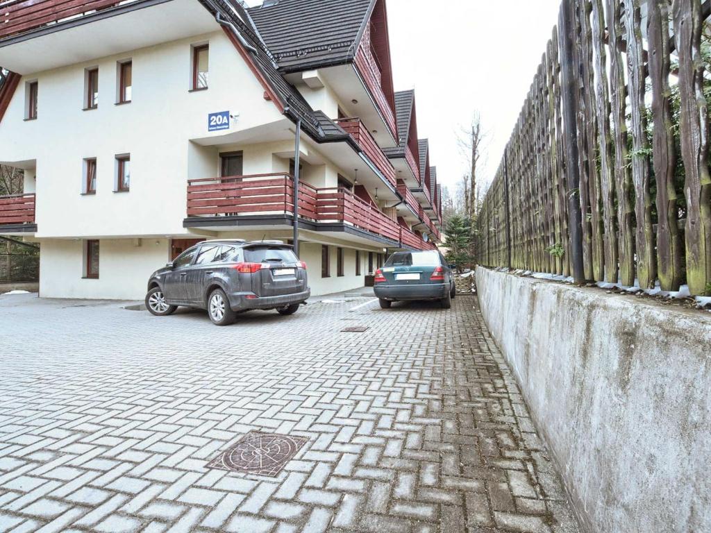 dwa samochody zaparkowane przed budynkiem w obiekcie VisitZakopane - Himalaya Apartment w Zakopanem