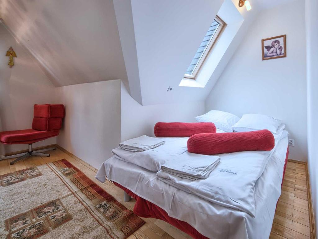sypialnia z łóżkiem z czerwonymi poduszkami i czerwonym krzesłem w obiekcie VisitZakopane - Himalaya Apartment w Zakopanem