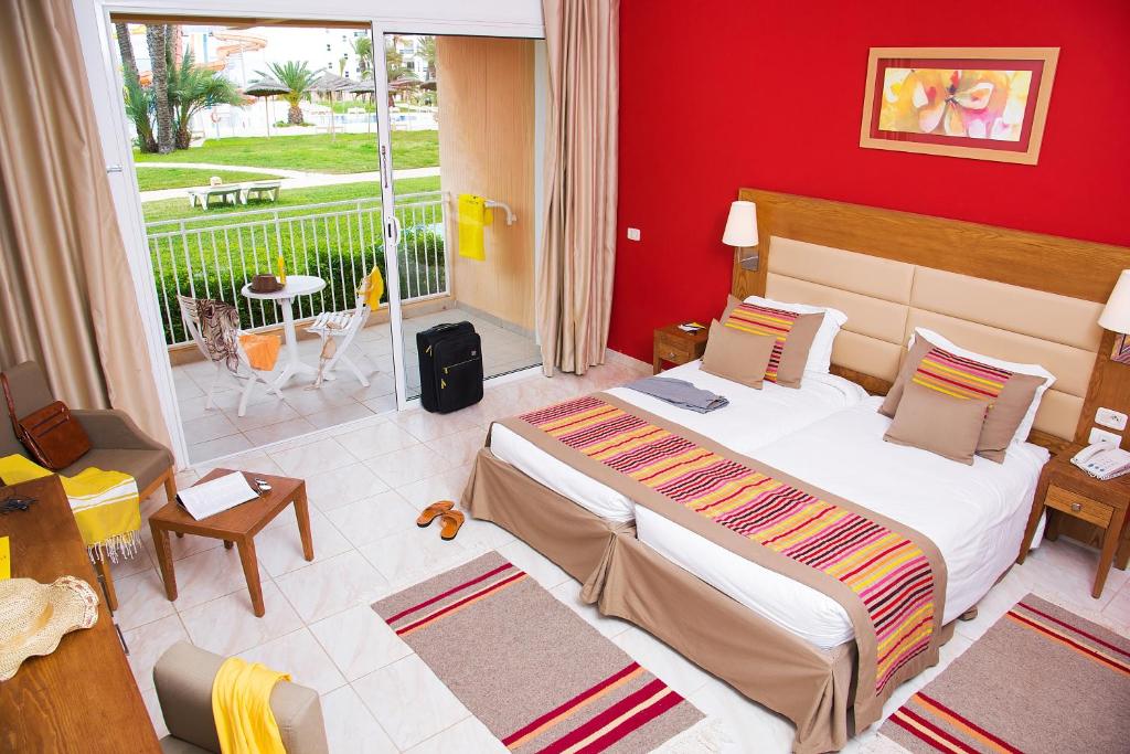 a bedroom with a large bed with a red wall at AQI Skanes Resort in Monastir