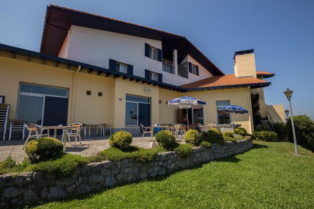 une maison avec une terrasse dotée de tables et de parasols dans l'établissement Hotel Ermintxo, à Ea