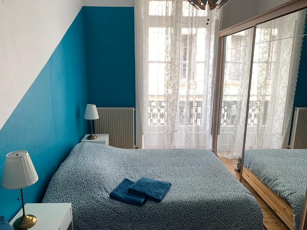 a blue bedroom with two beds and a window at 020 CHIC & COSY GRAND APPART 57m2 HYPERCENTRE WIFI SMART TV NETFLIX in Saint-Étienne