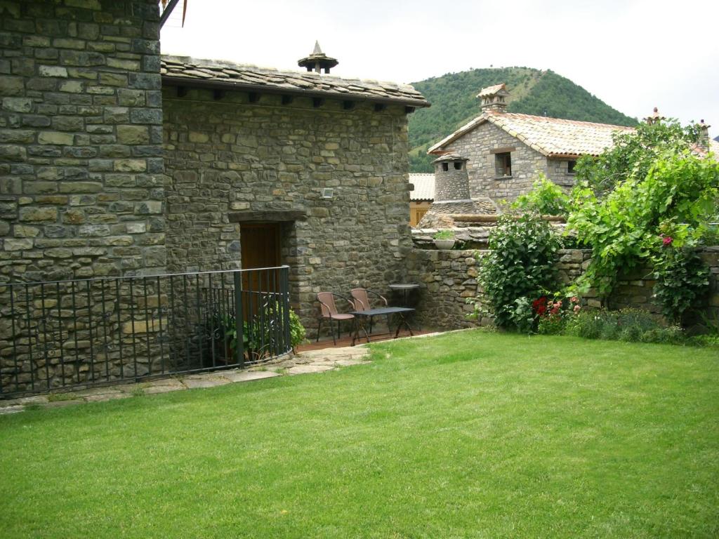 une maison en pierre avec une cour dotée d'une table et de chaises dans l'établissement El Castillo, à Boltaña