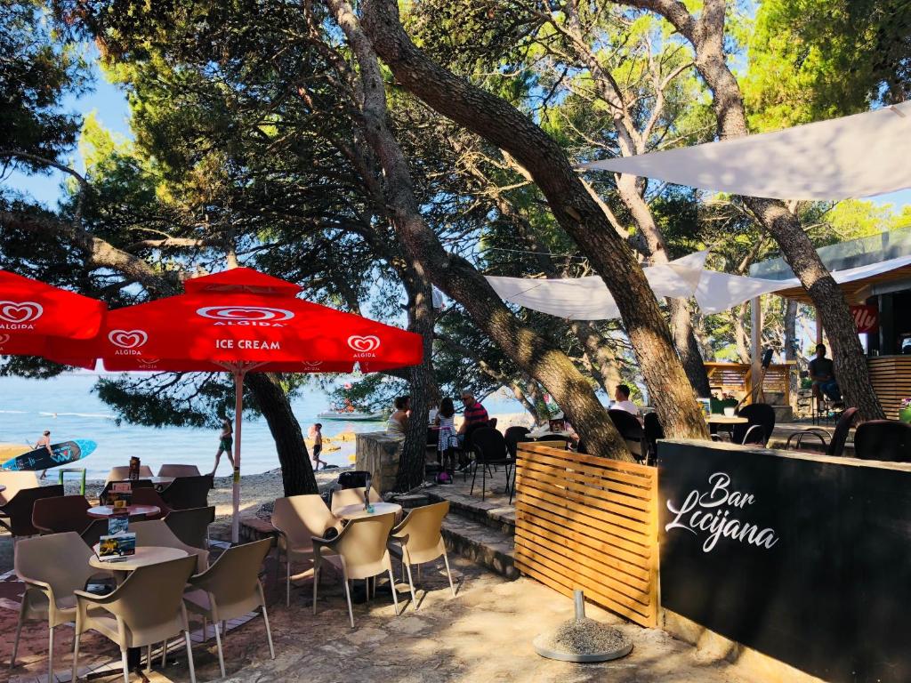 a restaurant with a red umbrella on the beach at Camping Kozarica Mobile Homes in Pakoštane