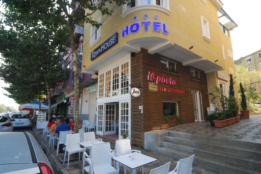 un hôtel avec des tables et des chaises blanches à l'extérieur dans l'établissement Hotel Town House, à Tirana
