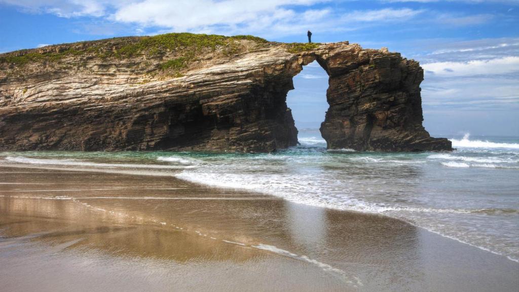 a person standing on a rock formation in the ocean at O Lar de Carmiña in Devesa