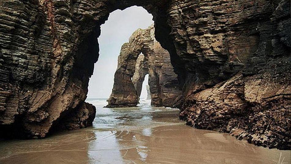 an arch in a rock formation in the water at O Lar de Carmiña in Devesa